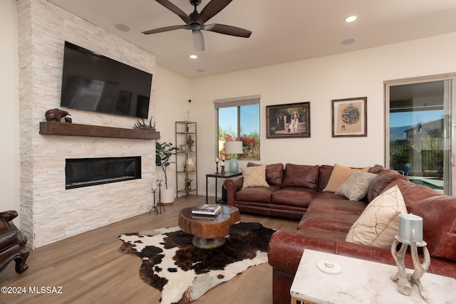 living room with hardwood / wood-style floors, ceiling fan, and a fireplace