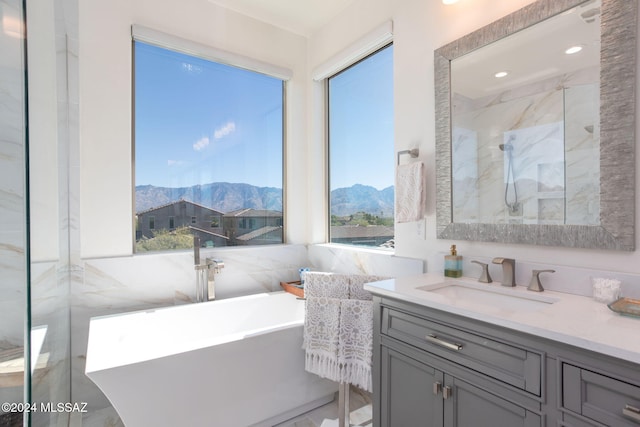 bathroom featuring a mountain view, vanity, tile walls, and independent shower and bath