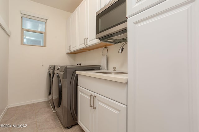 laundry room featuring light tile patterned flooring, cabinets, sink, and washing machine and clothes dryer