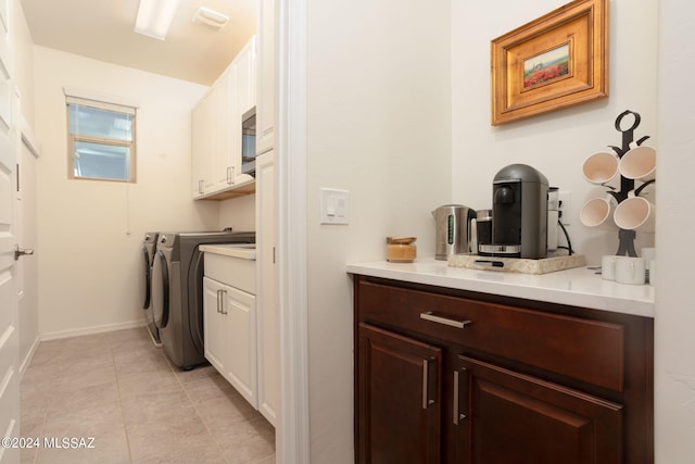 laundry area with washer and dryer, light tile patterned flooring, and cabinets