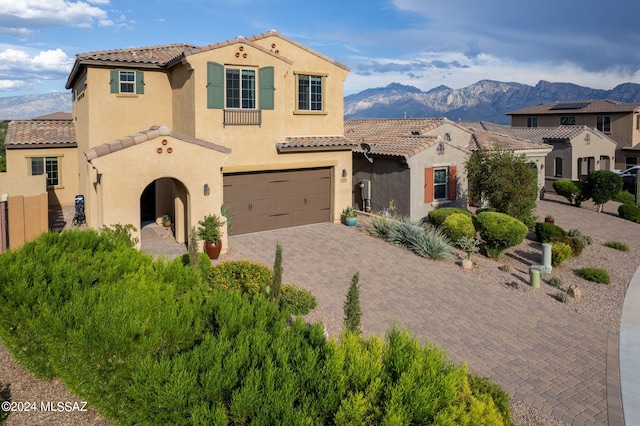 mediterranean / spanish house with a tiled roof, a mountain view, decorative driveway, and stucco siding