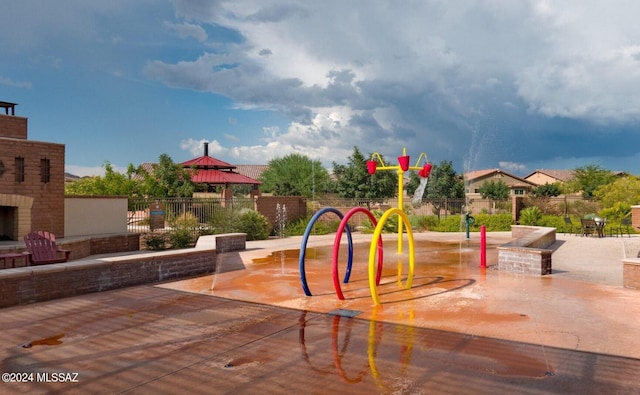 view of play area with a gazebo and an outdoor brick fireplace