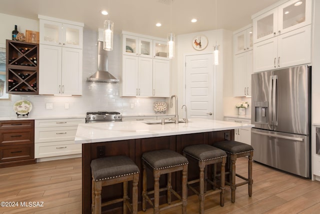 kitchen with appliances with stainless steel finishes, hardwood / wood-style flooring, white cabinetry, and a kitchen island with sink