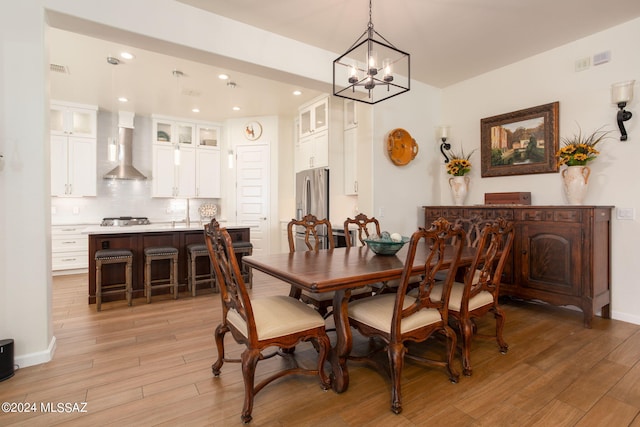 dining area featuring light wood-type flooring and a notable chandelier