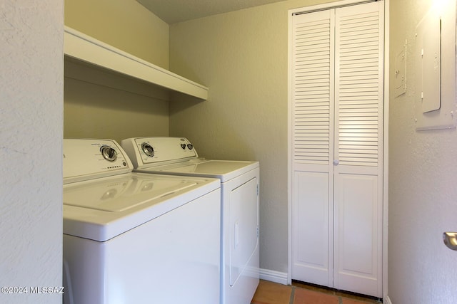 laundry room featuring washer and dryer, electric panel, and dark tile patterned flooring