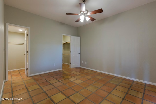 unfurnished bedroom featuring tile patterned flooring, ceiling fan, a walk in closet, and a closet