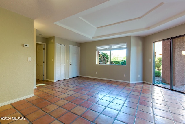 tiled empty room with a raised ceiling