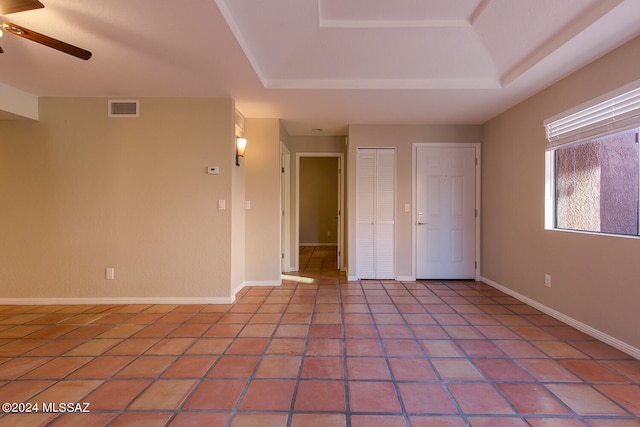 tiled spare room featuring a tray ceiling and ceiling fan