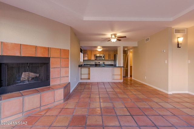 unfurnished living room featuring light tile patterned floors, ceiling fan, and a tiled fireplace