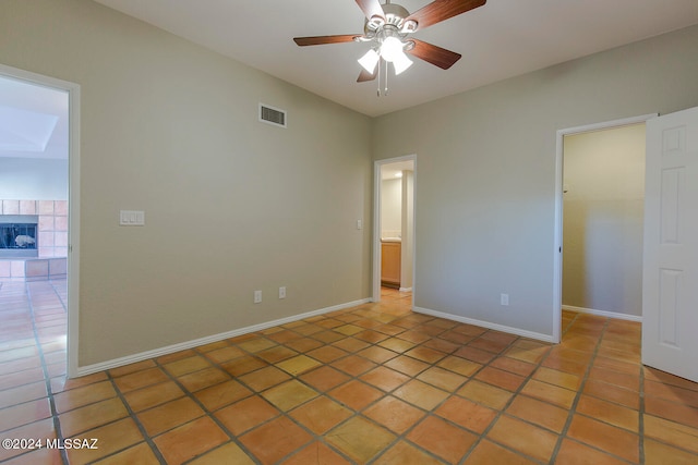 empty room with tile patterned flooring, ceiling fan, and a tile fireplace