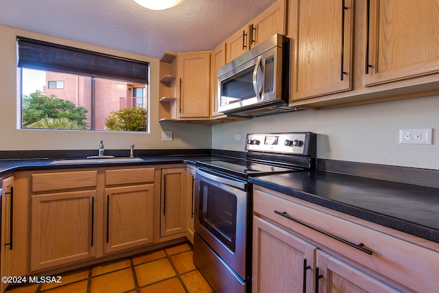 kitchen featuring a textured ceiling, light tile patterned flooring, sink, and stainless steel appliances