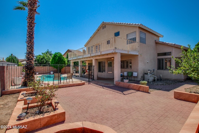 rear view of property featuring a balcony and a patio area