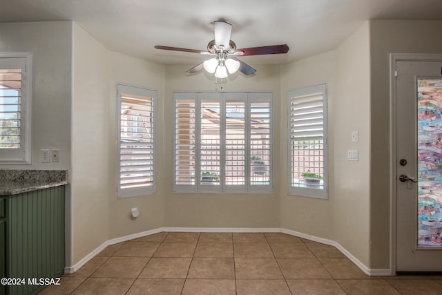 unfurnished dining area featuring a wealth of natural light, light tile patterned floors, and ceiling fan