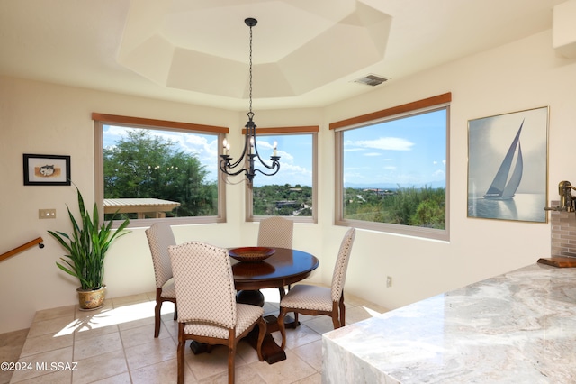 dining space featuring an inviting chandelier, a raised ceiling, and light tile patterned flooring