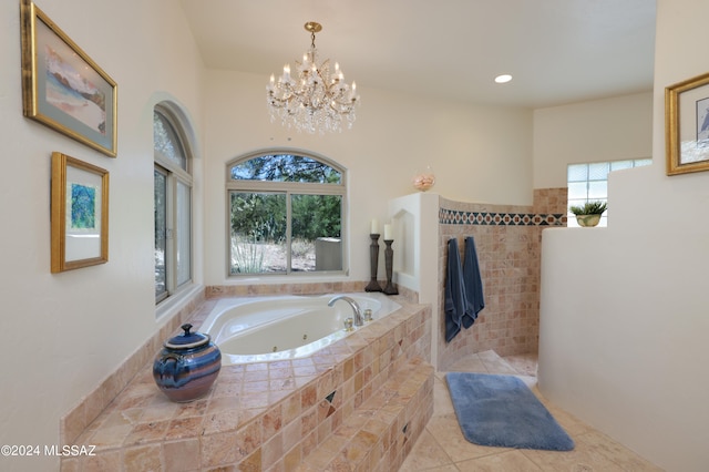 bathroom featuring a notable chandelier, tile patterned flooring, and tiled tub