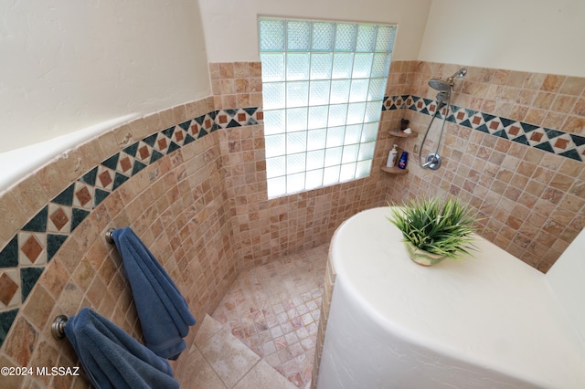 bathroom with tile walls, a wealth of natural light, tile patterned floors, and walk in shower