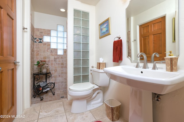 bathroom featuring tiled shower, sink, and toilet