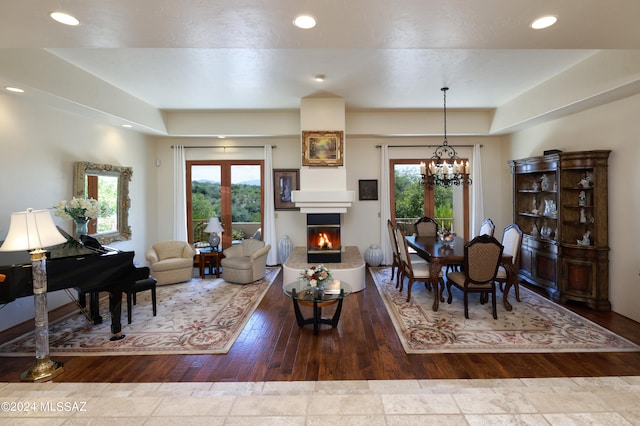 living room with a healthy amount of sunlight, hardwood / wood-style floors, a chandelier, and a tray ceiling