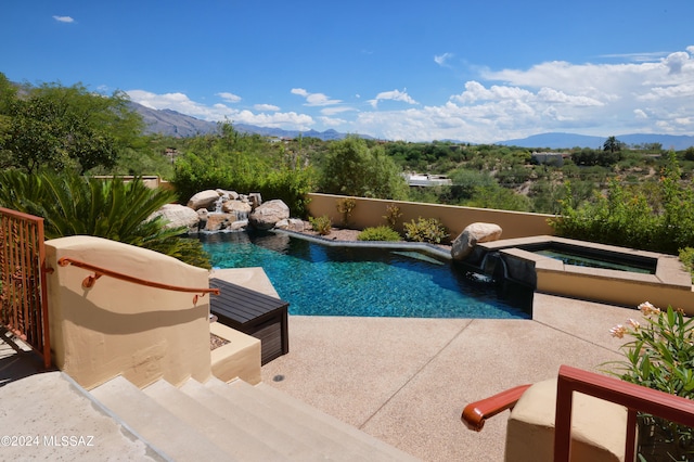 view of pool featuring an in ground hot tub, pool water feature, a mountain view, and a patio area