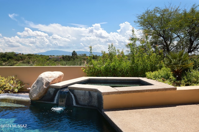 view of pool featuring a mountain view and an in ground hot tub