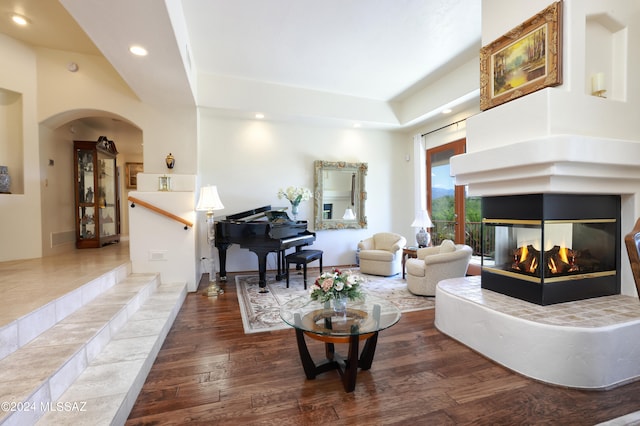 living room with a multi sided fireplace and dark wood-type flooring