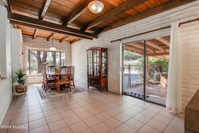 dining room with beam ceiling, brick wall, light tile patterned floors, and wood ceiling