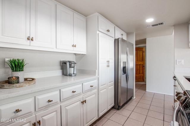 kitchen featuring sink, white cabinetry, light tile patterned floors, appliances with stainless steel finishes, and light stone counters