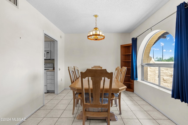 tiled dining room with an inviting chandelier and a textured ceiling