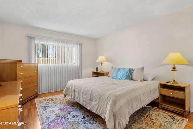 bedroom with a textured ceiling and hardwood / wood-style flooring