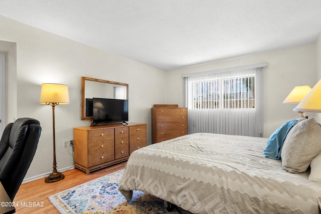 bedroom featuring a textured ceiling and light hardwood / wood-style floors