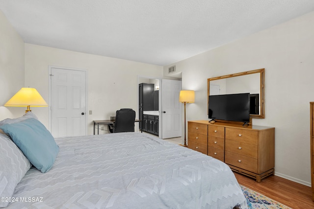 bedroom with light wood-type flooring and ensuite bathroom