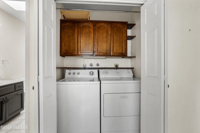 clothes washing area featuring light tile patterned floors, independent washer and dryer, and cabinets