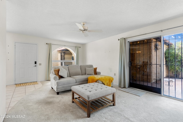 living room with a textured ceiling, ceiling fan, and light tile patterned floors