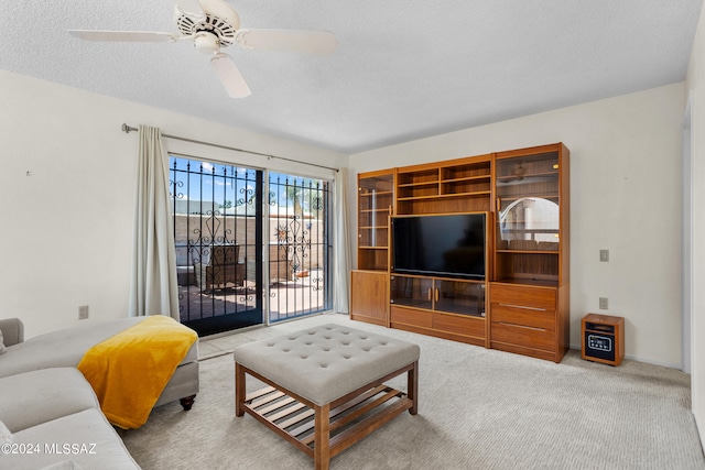 carpeted living room with a textured ceiling and ceiling fan