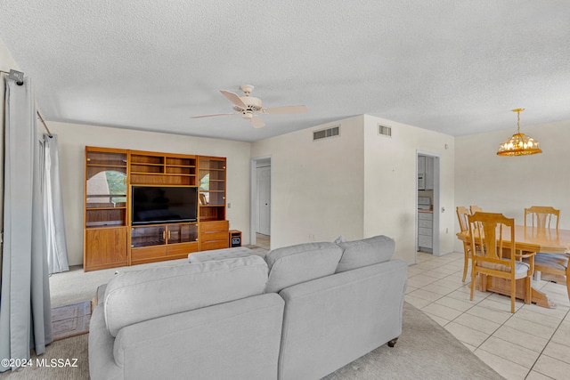 tiled living room featuring a textured ceiling and ceiling fan with notable chandelier