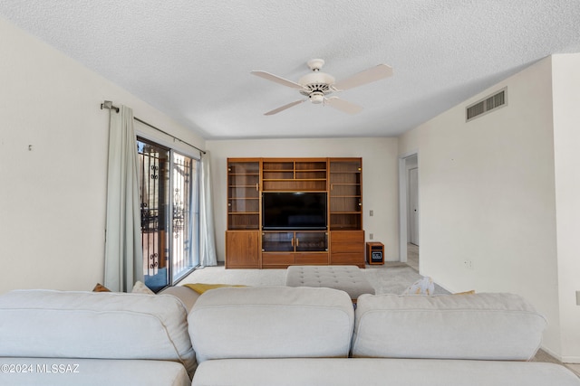 living room featuring light colored carpet, ceiling fan, and a textured ceiling