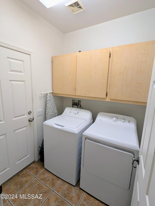 laundry room with washing machine and clothes dryer, cabinets, and tile patterned flooring