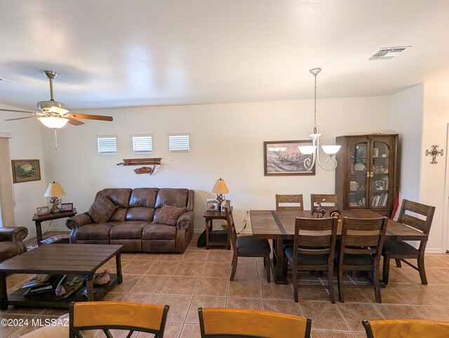 tiled living room with ceiling fan with notable chandelier