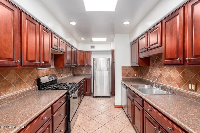 kitchen with appliances with stainless steel finishes, sink, tasteful backsplash, and light tile patterned flooring