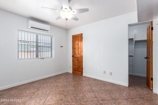 unfurnished bedroom featuring an AC wall unit, a closet, a walk in closet, tile patterned flooring, and ceiling fan