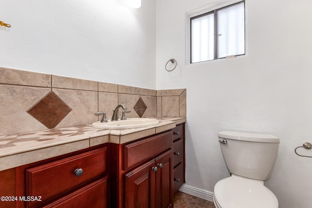 bathroom featuring vanity, toilet, and backsplash