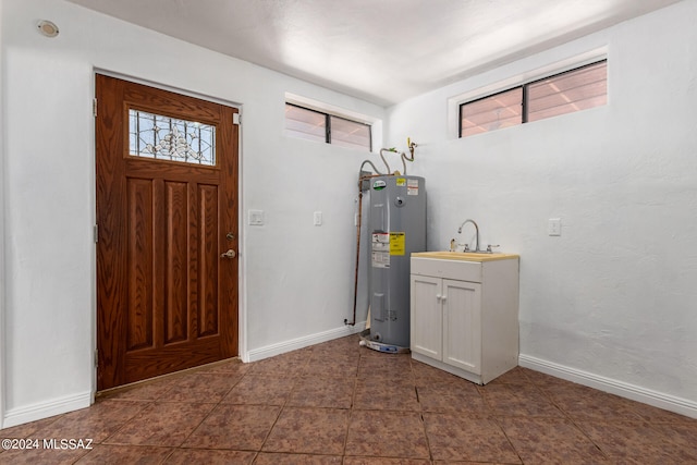 entrance foyer with water heater, sink, and dark tile patterned flooring