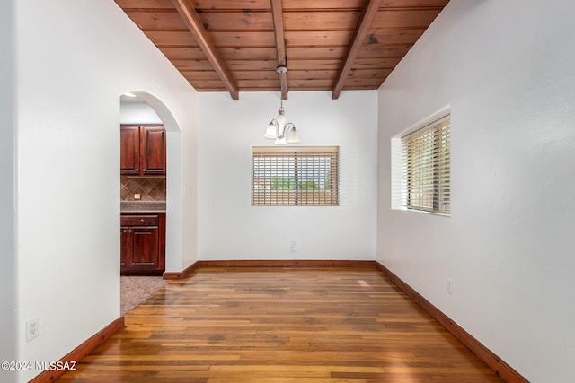 empty room with a chandelier, wood ceiling, hardwood / wood-style flooring, and lofted ceiling with beams