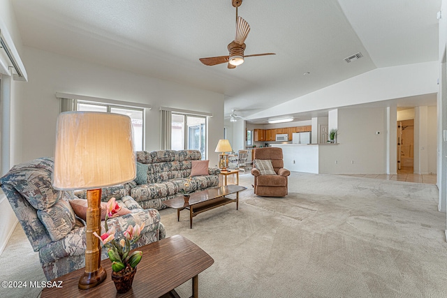 carpeted living room with ceiling fan and vaulted ceiling