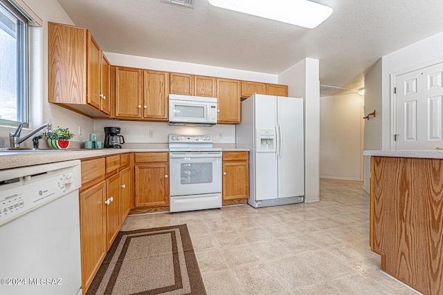 kitchen featuring a textured ceiling, sink, light tile patterned floors, and white appliances