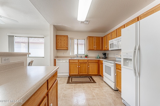 kitchen with white appliances, light tile patterned floors, sink, and ceiling fan