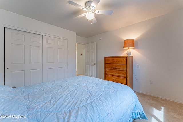 bedroom featuring light colored carpet, ceiling fan, and a closet