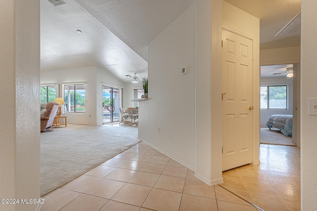 hall with a textured ceiling and light colored carpet