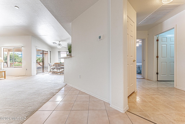 corridor with a textured ceiling and light colored carpet