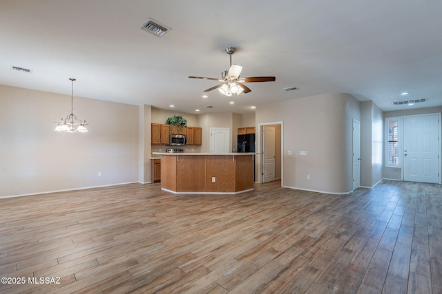 unfurnished living room with ceiling fan with notable chandelier and light hardwood / wood-style floors